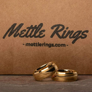 The Halpert Gold Men's Wedding Ring from Mettle Rings is both Dwight and Pam approved, and is also available with a Black or Silver finish. This wedding ring is forged from Tungsten Carbide. The Halpert Gold ring is available in 8mm width and features a Brushed Exterior Accents with Beveled Edges.